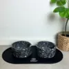 2 stilrene terrazzoskåle med et sort spiseunderlag. Perfekt til din hunds spisested.